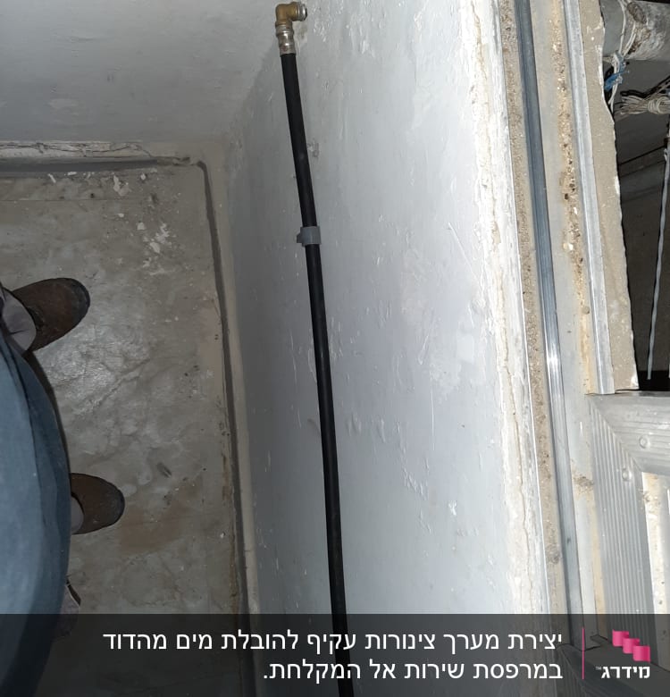 צינור מים שחור מחובר לקיר עם מחבר מתכת